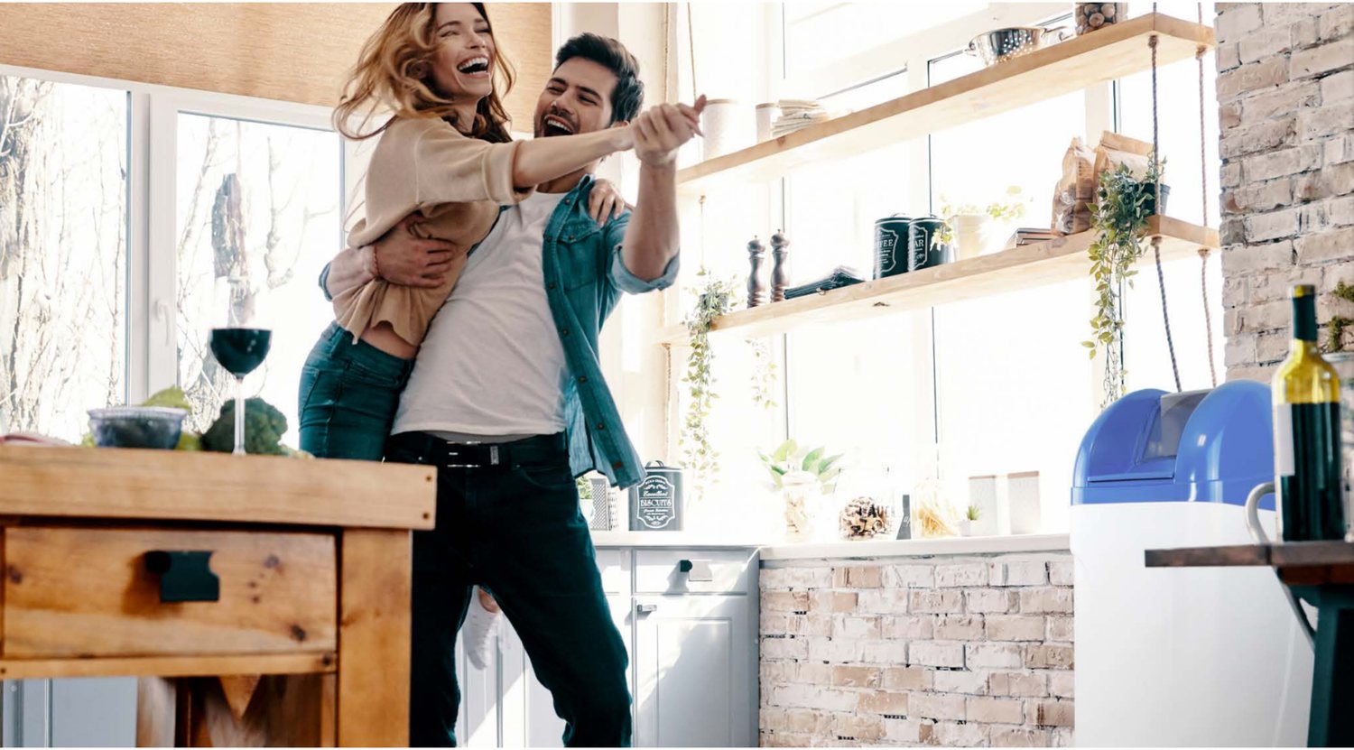 Couple souriant dans sa cuisine, adoucisseur ECB installé au sol