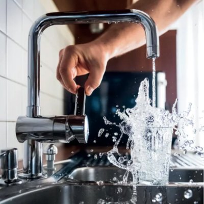 Eau qui coule d'un robinet et éclabousse un verre